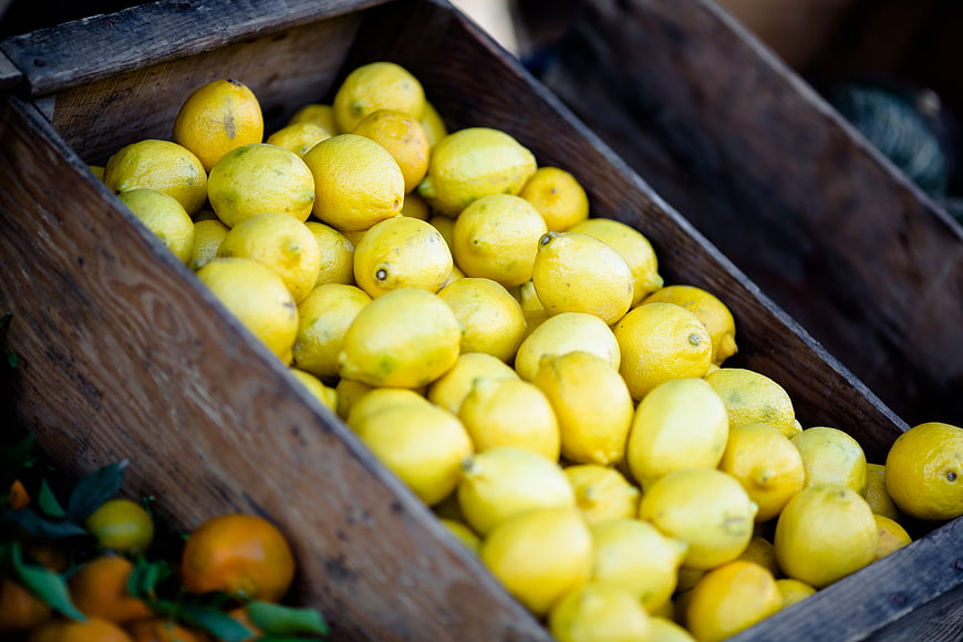 Fresh yellow lemons in a rustic wooden crate at market