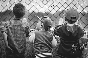 Three young boys watching through a chain-link fence