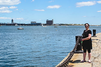 Woman standing on stone pier with harbor and city skyline background