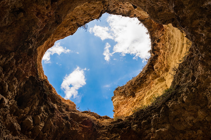 View of blue sky through rocky cave opening