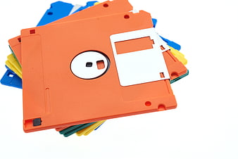 Stack of colorful vintage floppy disks on white background