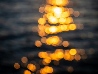 Abstract golden bokeh lights reflecting on dark water surface