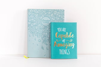 Inspirational teal notebook and floral planner on white background