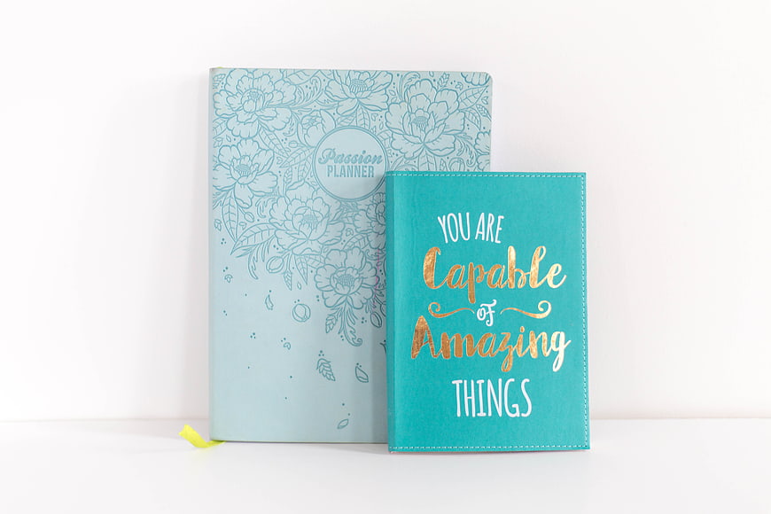 Inspirational teal notebook and floral planner on white background