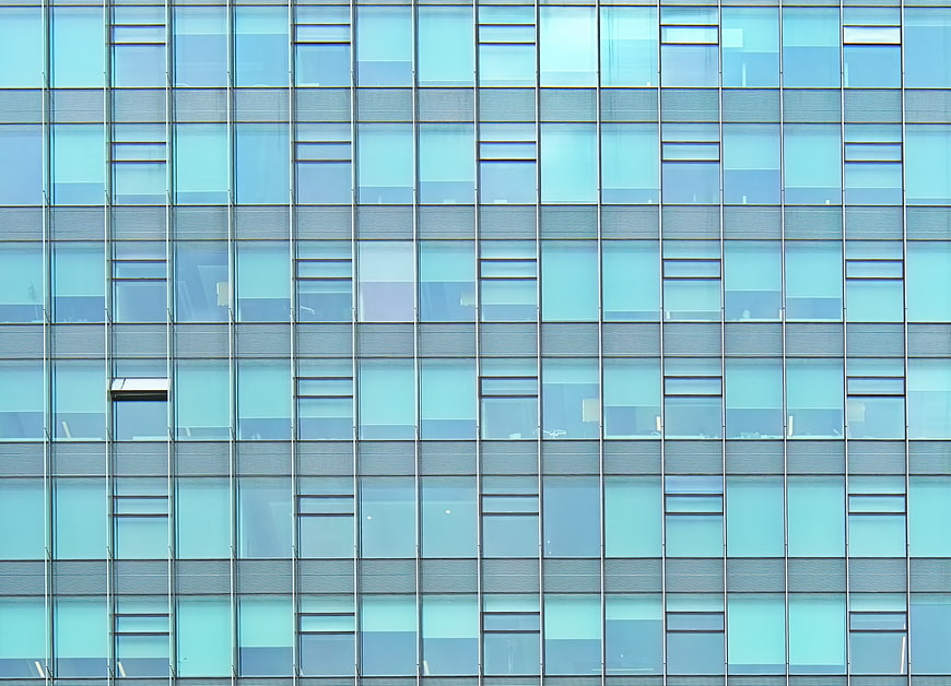 Modern glass office building facade with blue window grid pattern