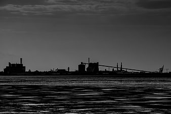 Black and white industrial skyline silhouette over water