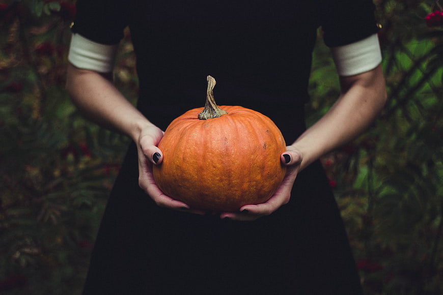 Woman holding orange pumpkin in autumn garden