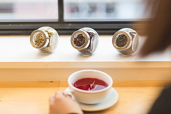 Cup of red tea with jars of loose leaf tea on windowsill