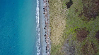 Aerial View of Turquoise Ocean Meeting Sandy Beach and Grassland