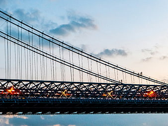 Suspension bridge silhouette at dusk with warm streetlights