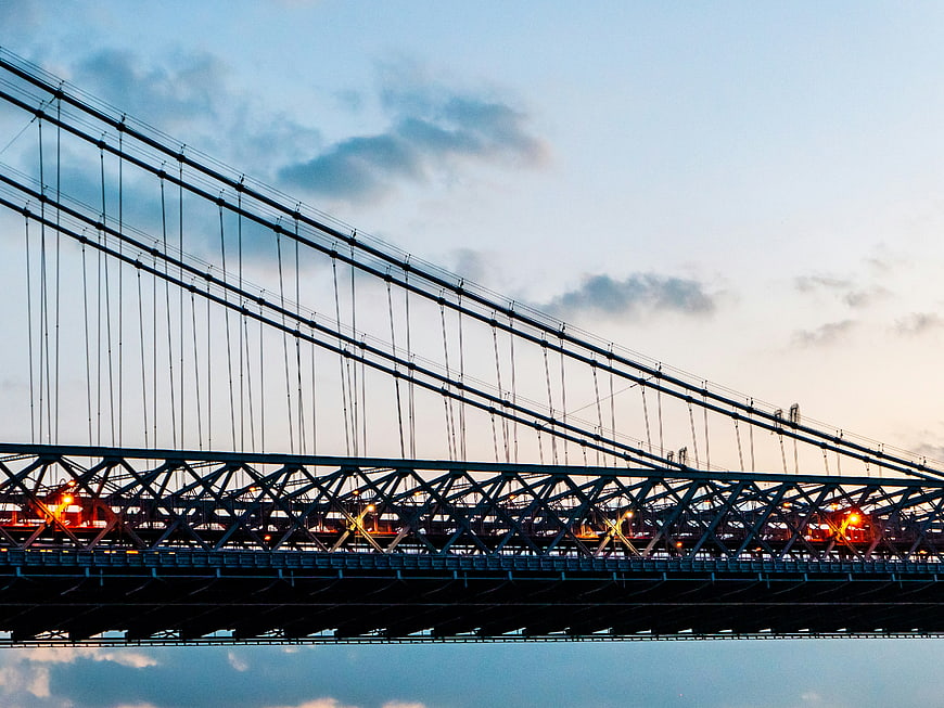 Suspension bridge silhouette at dusk with warm streetlights