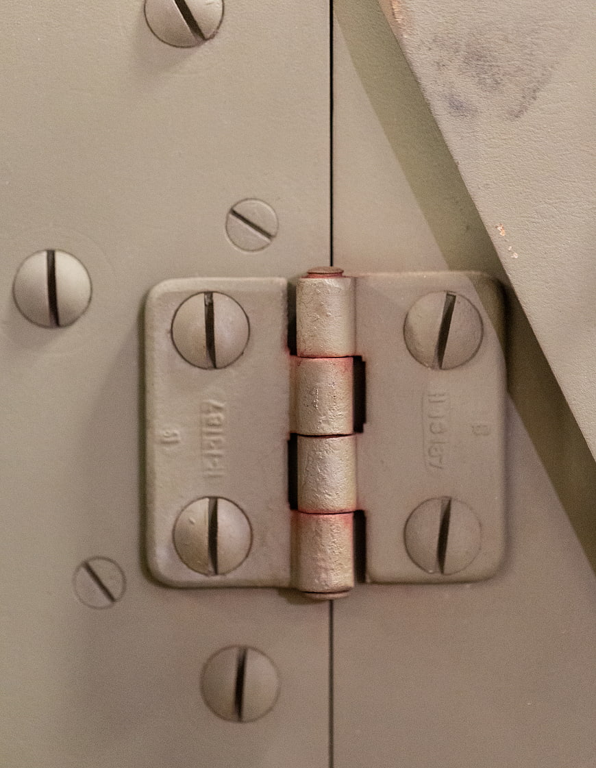 Close-up of industrial metal hinge on beige armored door