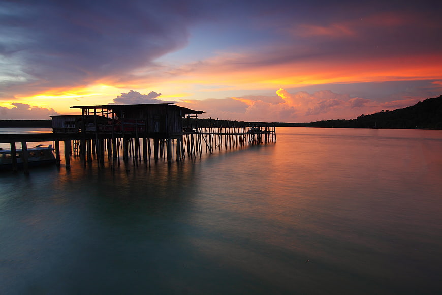 Stilt house silhouette at sunset over calm water