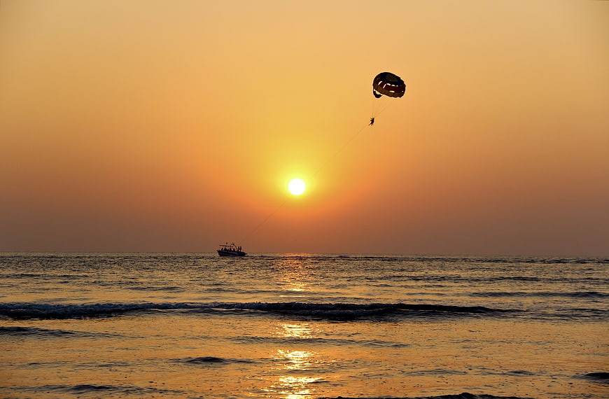 Parasailing Silhouette Against Golden Sunset Ocean Horizon
