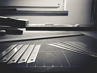 Black and white razor blades on a cutting mat in a workshop
