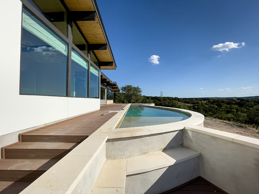 Modern luxury home with infinity pool overlooking green landscape