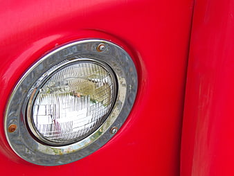 Close-up of vintage red car headlight with chrome rim