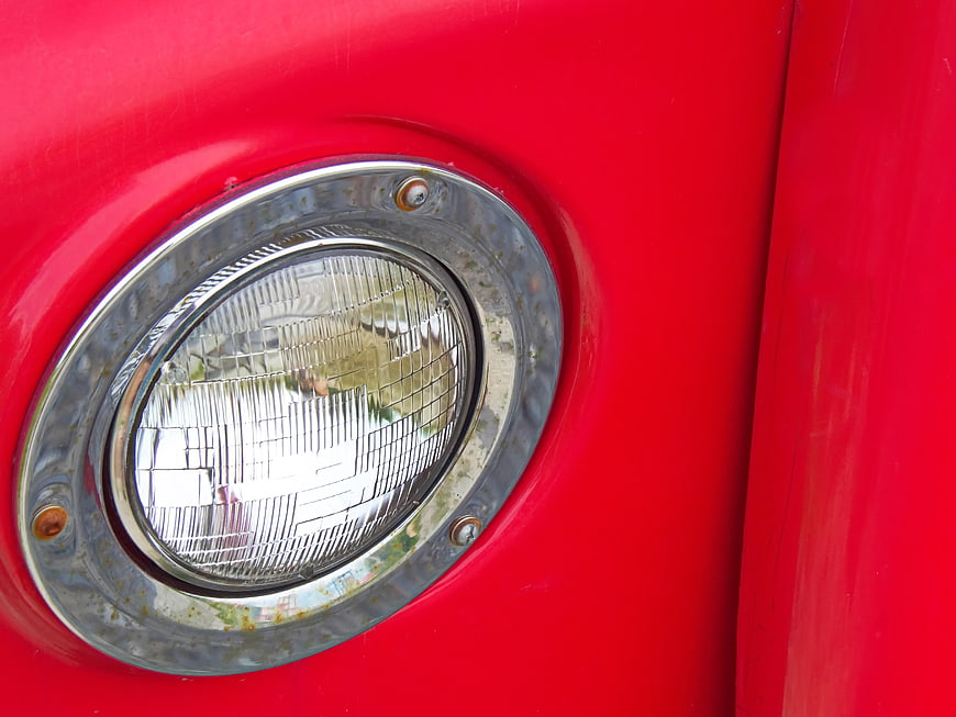Close-up of vintage red car headlight with chrome rim