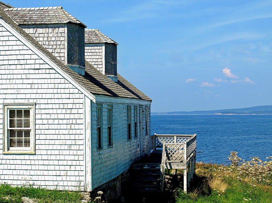 Weathered white coastal cottage overlooking the blue ocean