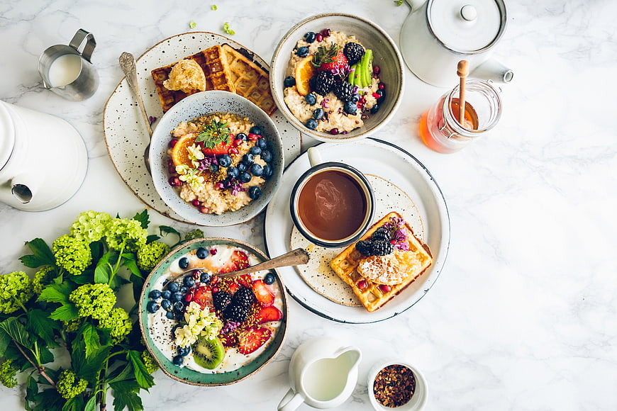 Overhead view of healthy breakfast with waffles, oatmeal, and fresh berries