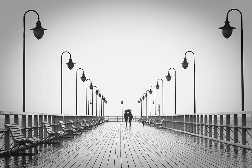 Couple Walking Under Umbrella on Rainy Pier