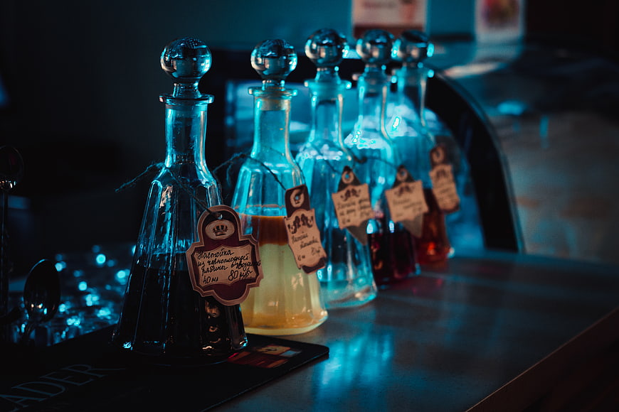 Row of glass decanters with colorful liquids on a bar counter