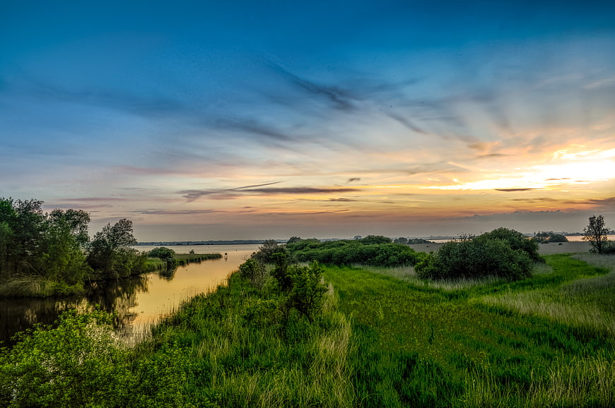 Serene sunset landscape over Zuidlaardermeer lake with green banks