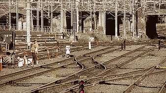 Railway Worker Standing Near Tracks in Industrial Yard