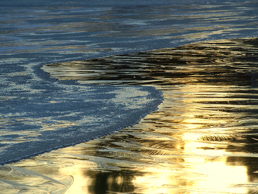 Golden sunlight reflecting on frozen ice and water surface
