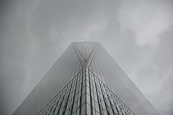 Low angle view of modern skyscraper against cloudy sky