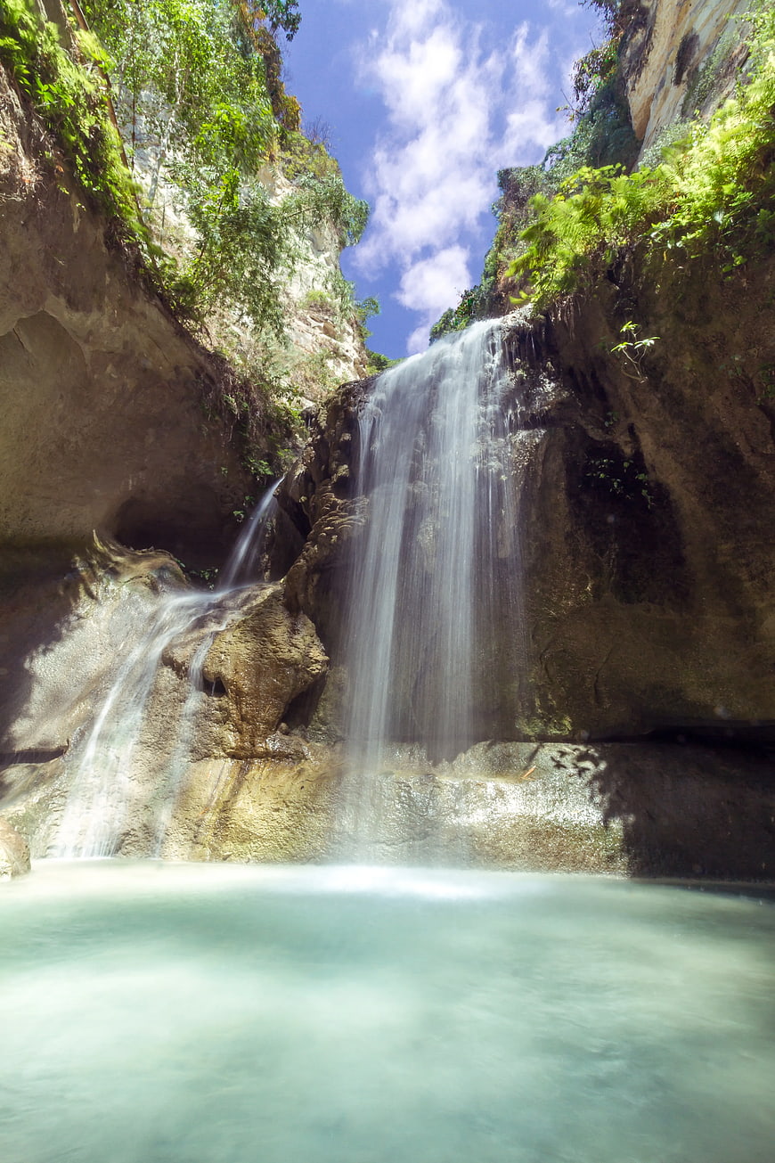 Serene waterfall cascading into a turquoise pool in a lush canyon