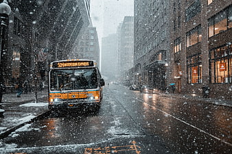 Yellow City Bus Driving Through Heavy Snowstorm in Urban Street