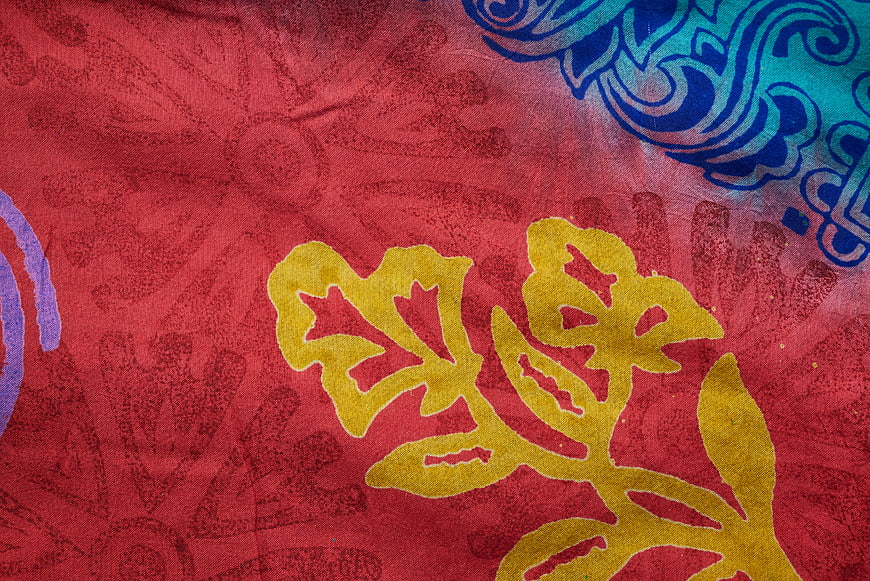 Close-up of vibrant red textile with yellow and blue floral patterns