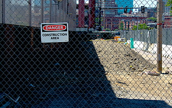 Danger construction area sign on chain link fence