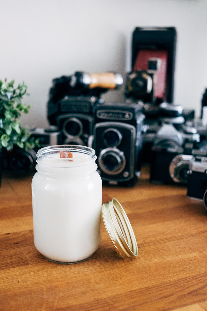 White Soy Candle in Mason Jar with Vintage Cameras Background