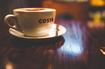 Costa Coffee Cup on Wooden Table with Warm Lighting