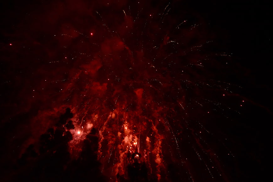 Red fireworks exploding in the night sky with smoke