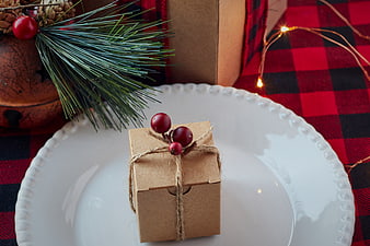 Christmas gift box on white plate with pine and plaid