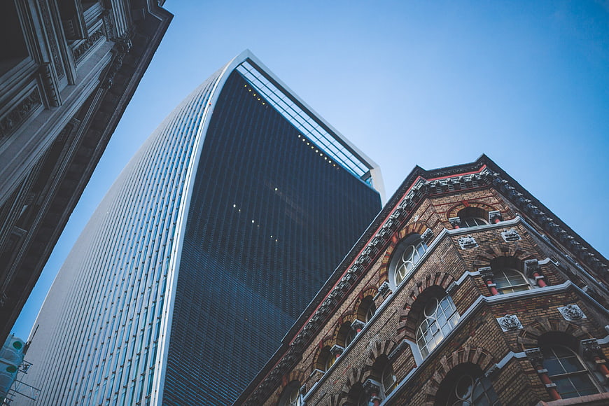 Low angle view of modern skyscraper and historic brick building