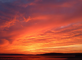 Vibrant Orange Sunset Over Coastal Hills and Ocean