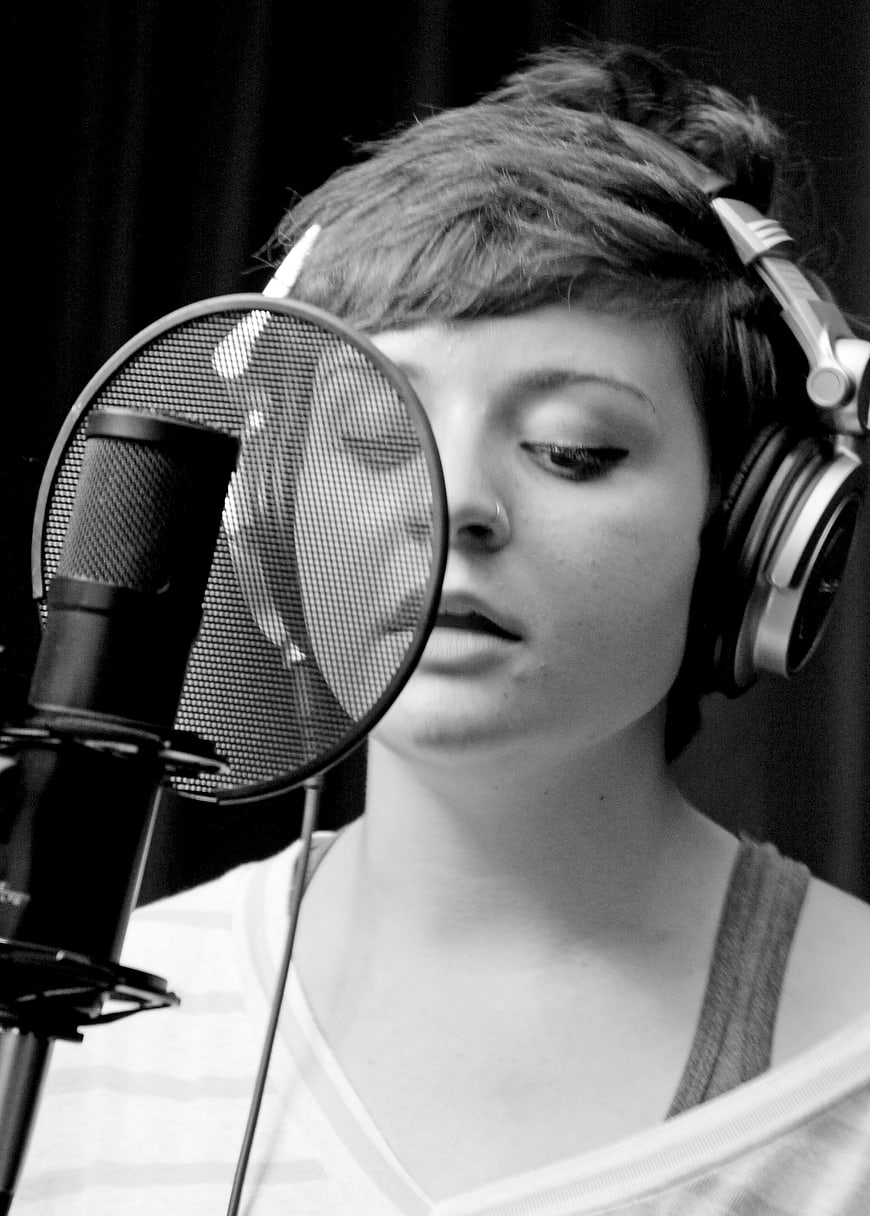 Woman singing into microphone in recording studio