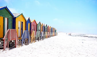 Colorful Beach Huts on White Sand Under Blue Sky