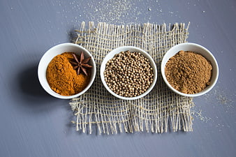 Top view of turmeric, coriander, and nutmeg in white bowls
