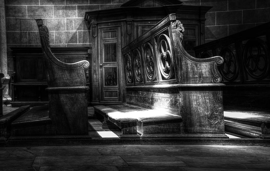 Black and white photo of ornate wooden church pews
