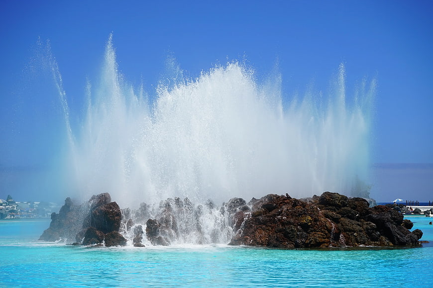 Dramatic Geysers Erupting from Volcanic Rocks in Turquoise Water
