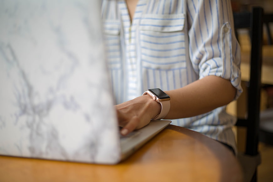 Woman Typing on Laptop with Smartwatch in Cafe