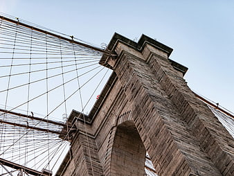Low angle view of Brooklyn Bridge stone tower and cables