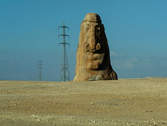 Carved Stone Face Sculpture in Desert Landscape with Power Lines