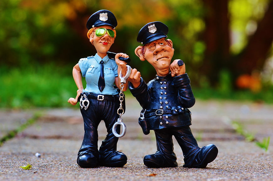 Caricature Police Figurines with Handcuffs on Path