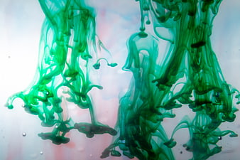 Abstract green ink swirling in water with soft pastel background